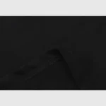 Close-up of the black Hellstar Path To Paradise T-Shirt fabric, showcasing visible stitching and a folded edge against a light gray background. The texture and seam detail emphasize the high-quality material and craftsmanship.