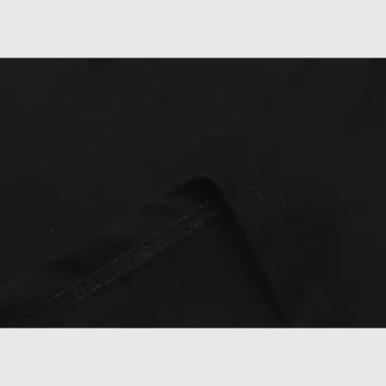 Close-up of the black Hellstar Path To Paradise T-Shirt fabric, showcasing visible stitching and a folded edge against a light gray background. The texture and seam detail emphasize the high-quality material and craftsmanship.